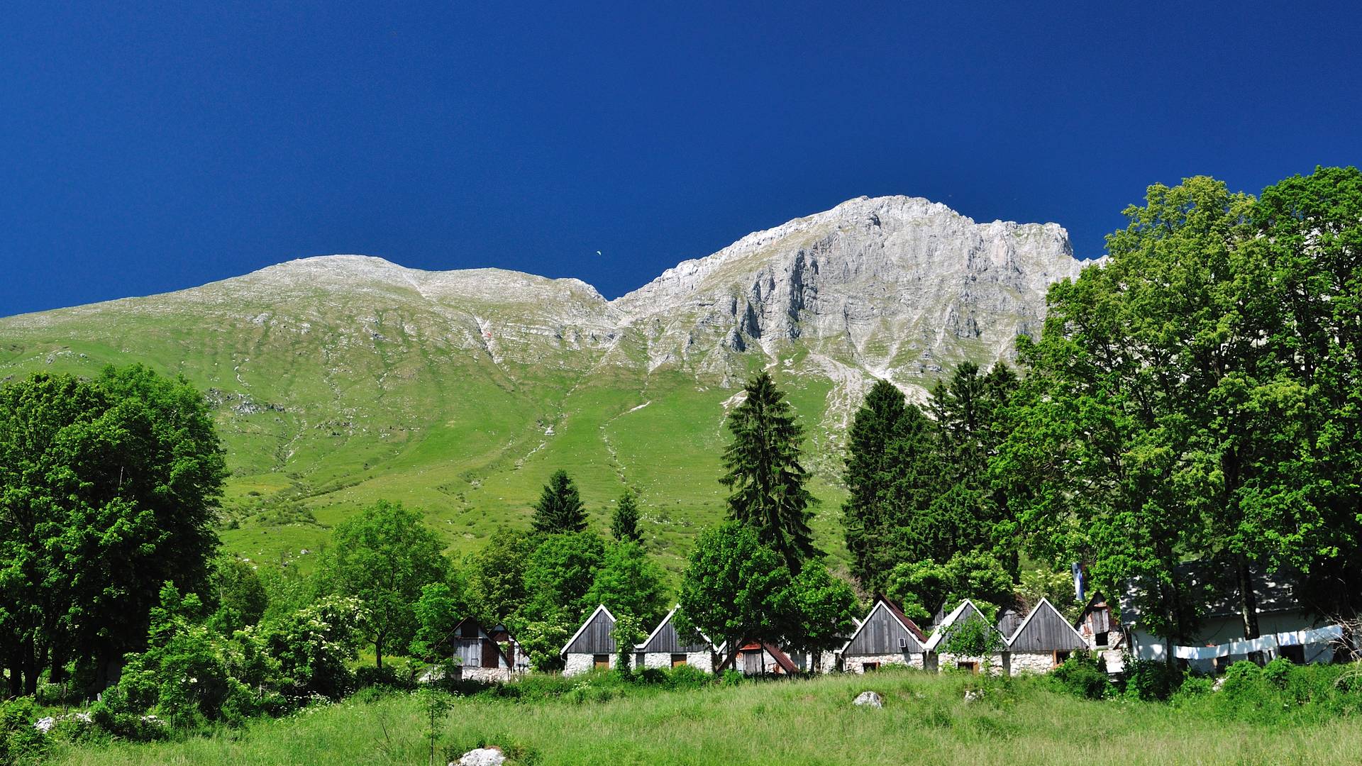 <p>Alpe Adria Trail Hütten, Planina Kuhinja, Kuhinja Alm mit Krn Bergmassiv im Hintergrund</p>