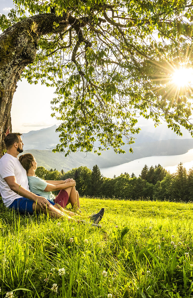 Mann und Frau sitzen im Schatten eines Baumes in der Via Paradiso.