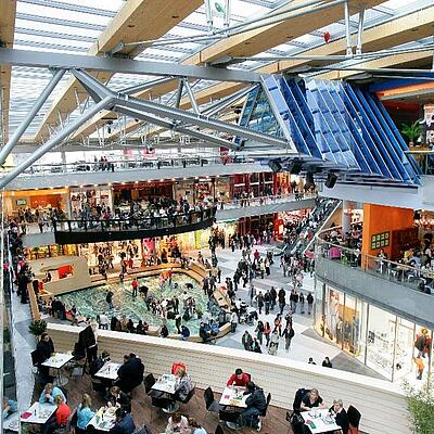Blick ins ATRIO Villach: mehrere Etagen mit Shops, Cafés, Restaurantbereich und vielen Besucher:innen unter einem Glasdach.