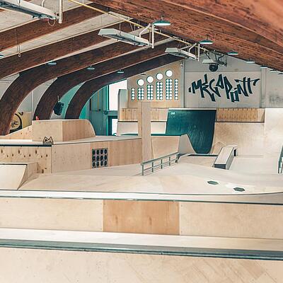 Leere Skatehalle mit Holzrampen und Hindernissen in der Megapoint Trendsporthalle Klagenfurt.