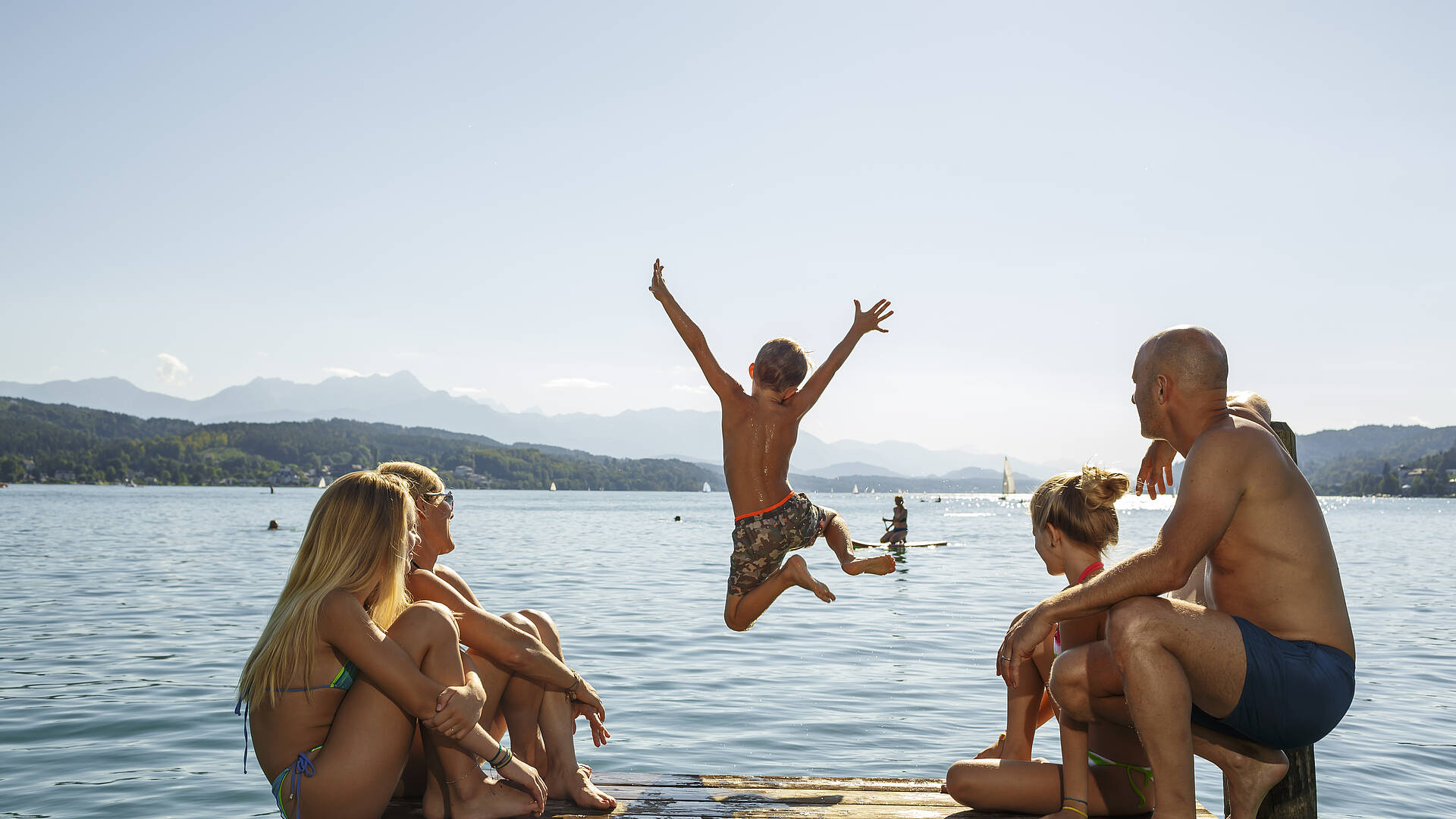 Junge spring vom Steg beim Baden mit der Familie im Werzerbad 