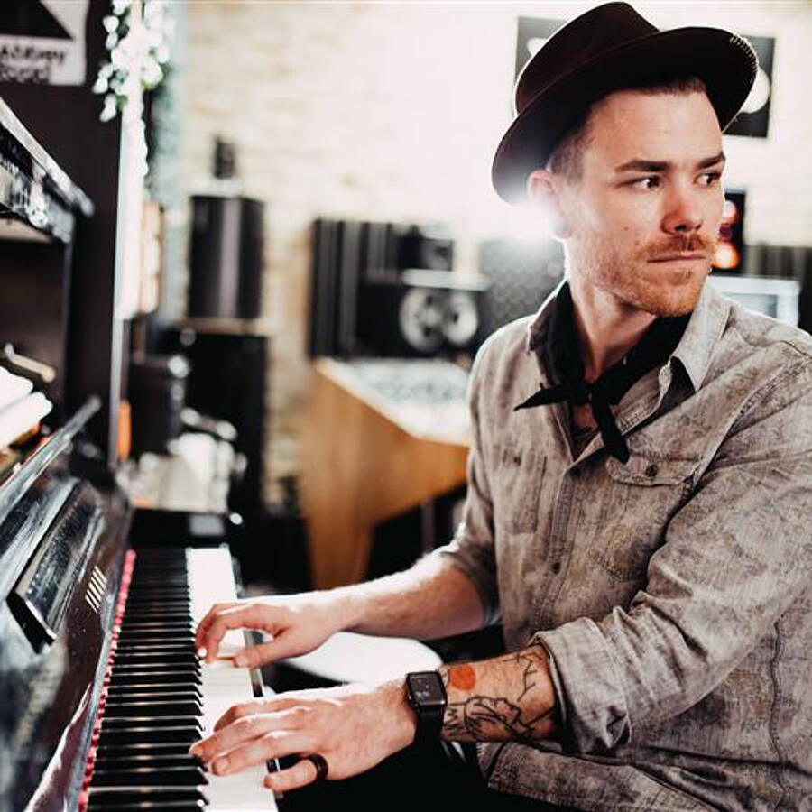 Matthias Ortner am Klavier sitzend, in seinem Tonstudio.