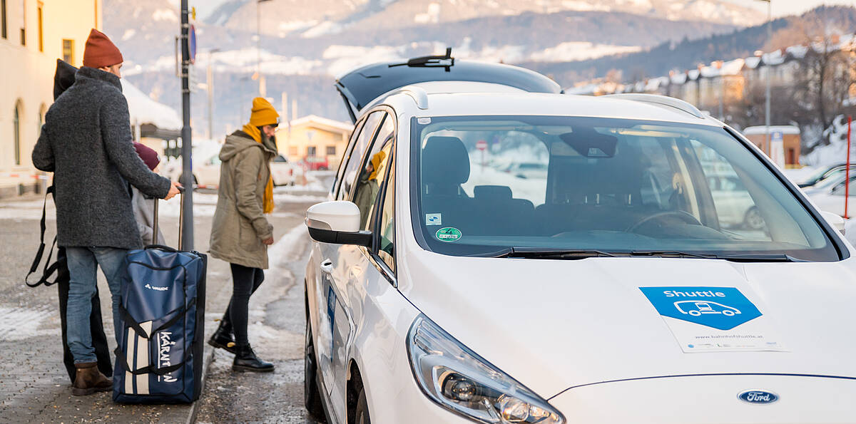 Pärchen mit dem Bahnhofshuttle zum Winterurlaub in Kärnten