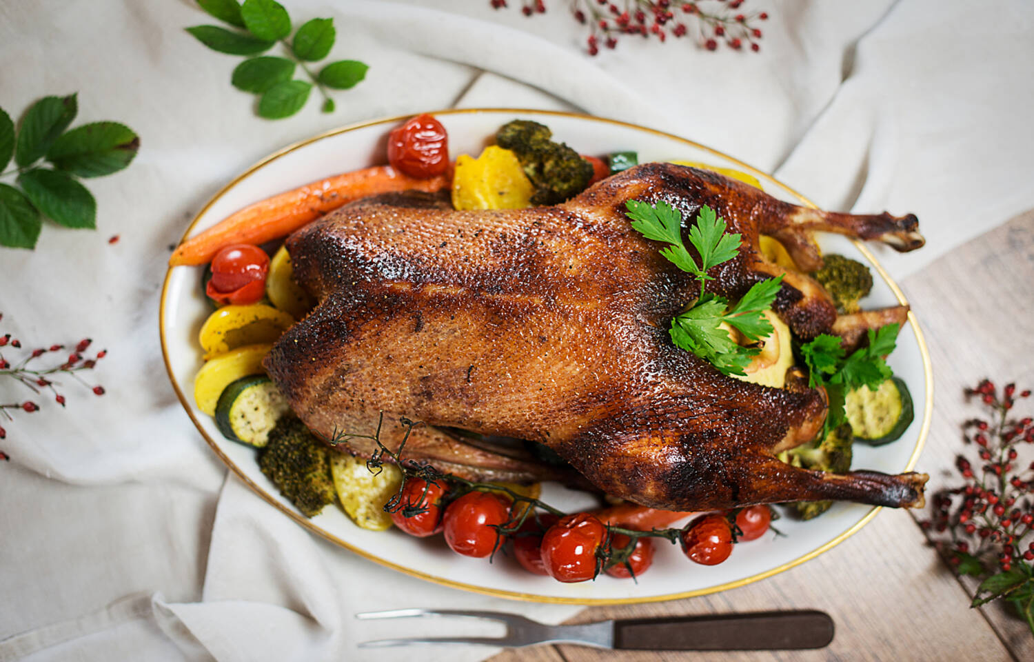 Eine Kaerntner Biogans mit Honigkruste und Erntegemuese appetitlich am Teller angerichet.