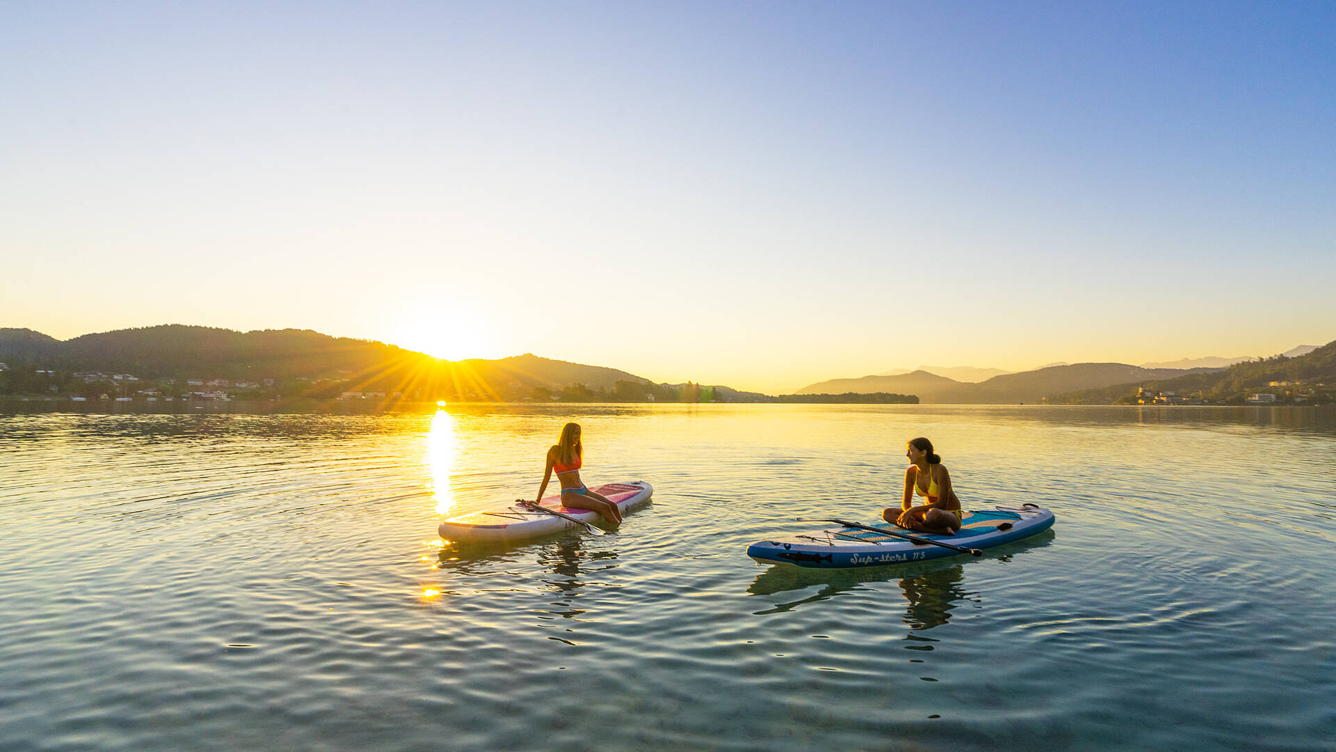 Zwei Damen bei Sonnenuntergang am Woerthersee mit Boot und Paddel