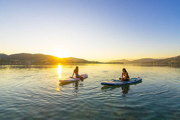 Zwei Damen bei Sonnenuntergang am Woerthersee mit Boot und Paddel