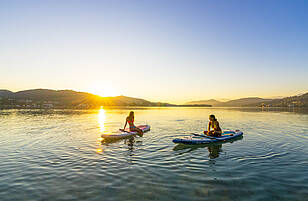 Zwei Damen bei Sonnenuntergang am Woerthersee mit Boot und Paddel