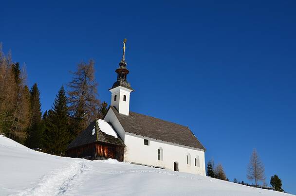 St. Anna Kirche in St. Lorenzen ob Reichenau im Schnee bei strahlend blauem Himmel