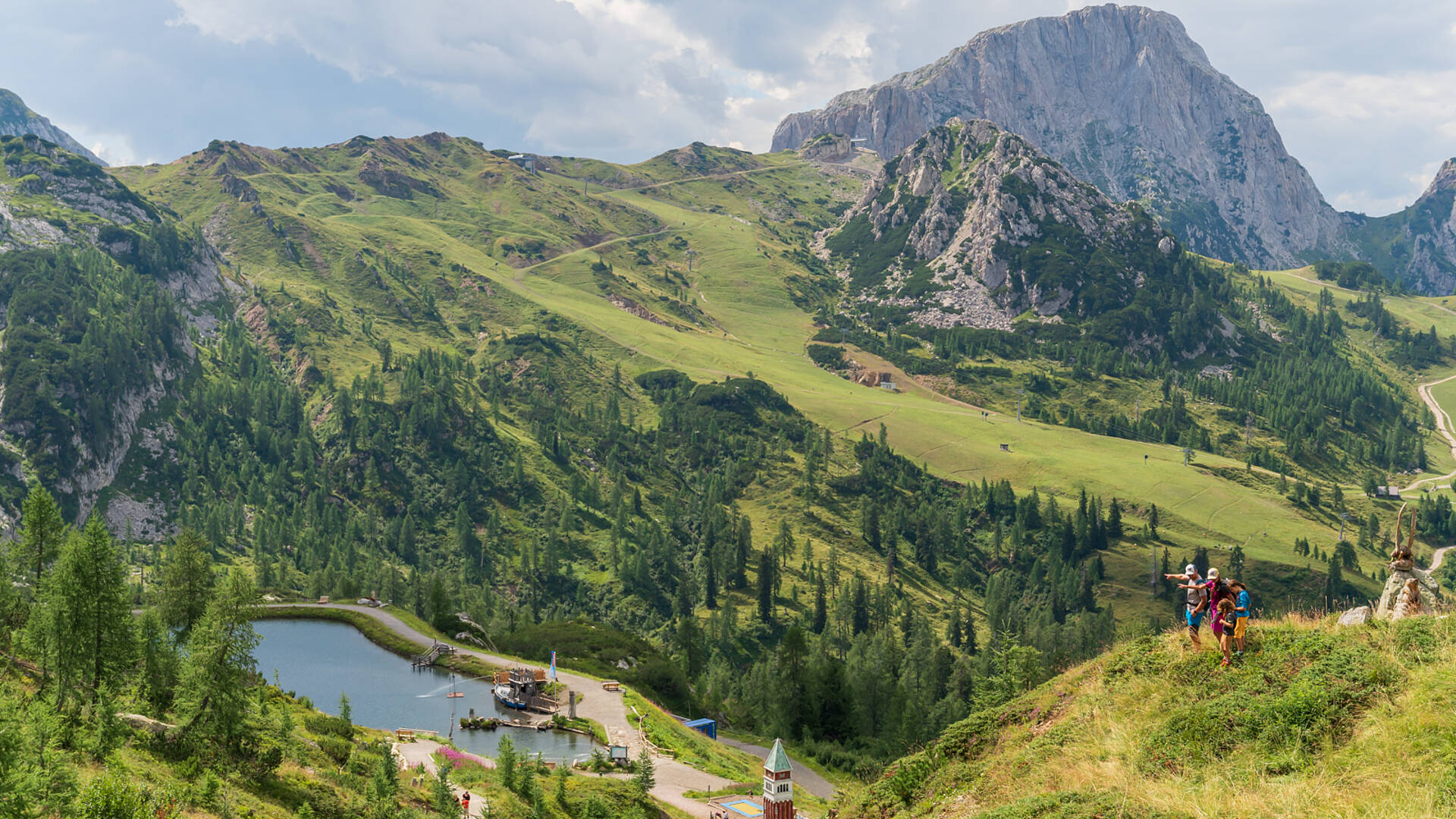 Bei einer Familienwanderung in der Region Nassfeld-Pressegger See genießen Wanderer einen Ausblick auf einen klaren Bach.