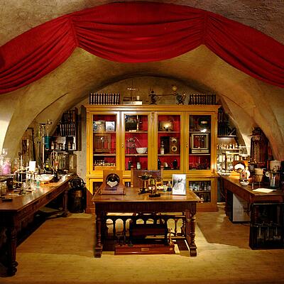 Historisches Labor im Auer von Welsbach Museum mit Holzmöbeln, Glasapparaturen, wissenschaftlichen Geräten und Büchern, das die Arbeitsumgebung des Erfinders Carl Auer von Welsbach zeigt.
