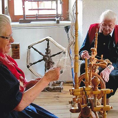 Zwei Frauen in traditioneller Kleidung beim Spinnen von Flachs im Brauchtumsmuseum Metnitz.
