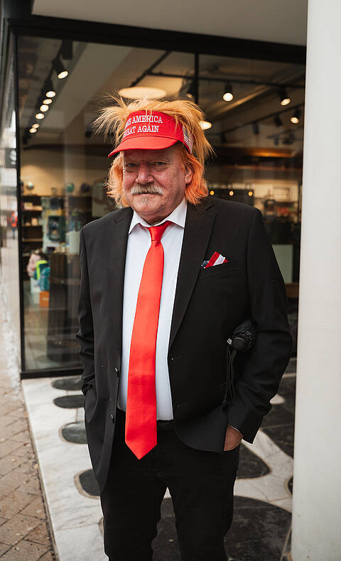 Mann mit auffälligem Kostüm und roter Kappe beim Villacher Fasching in Villach.