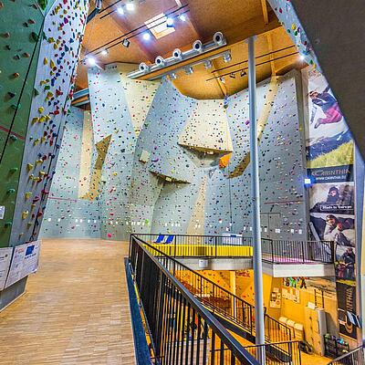 Innenansicht der Kletterhalle Mühldorf mit hohen, farblich markierten Kletterwänden.