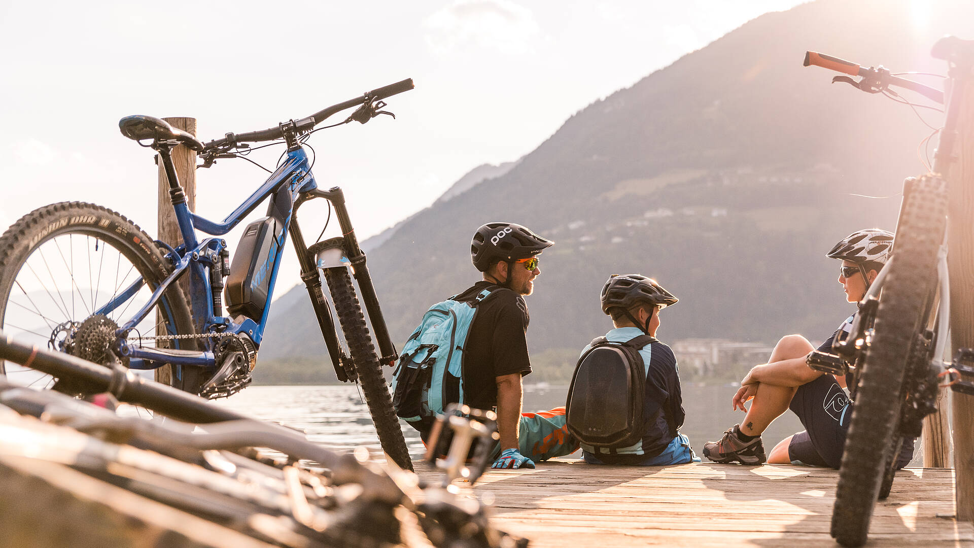 Eine Familie – Mama, Papa und ihr Kind – machen eine Pause während ihres Fahrradausflugs am Ossiacher See.