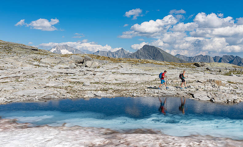 Pärchen beim Wandern am Tauernhöhenweg entlang eines Bergsees