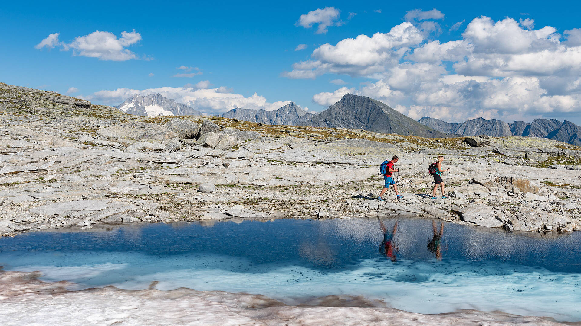 Pärchen beim Wandern am Tauernhöhenweg entlang eines Bergsees
