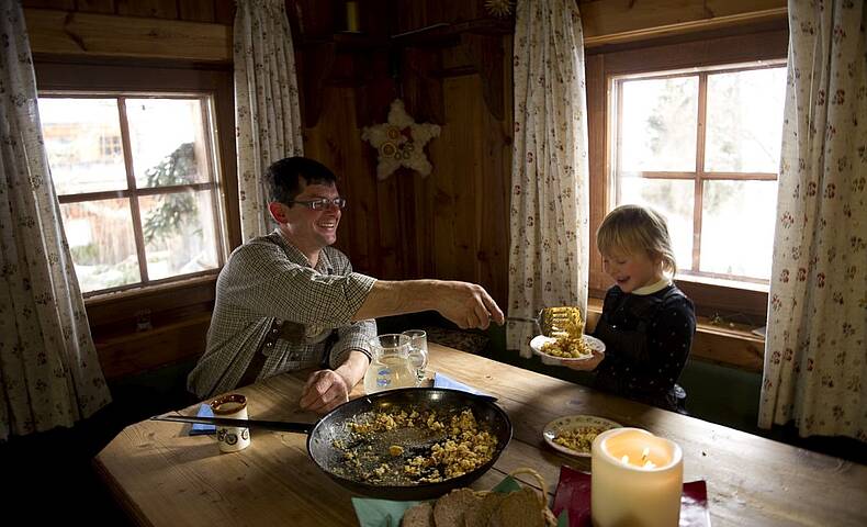 Mit dem Kind gemeinsam in der Hütte essen. 