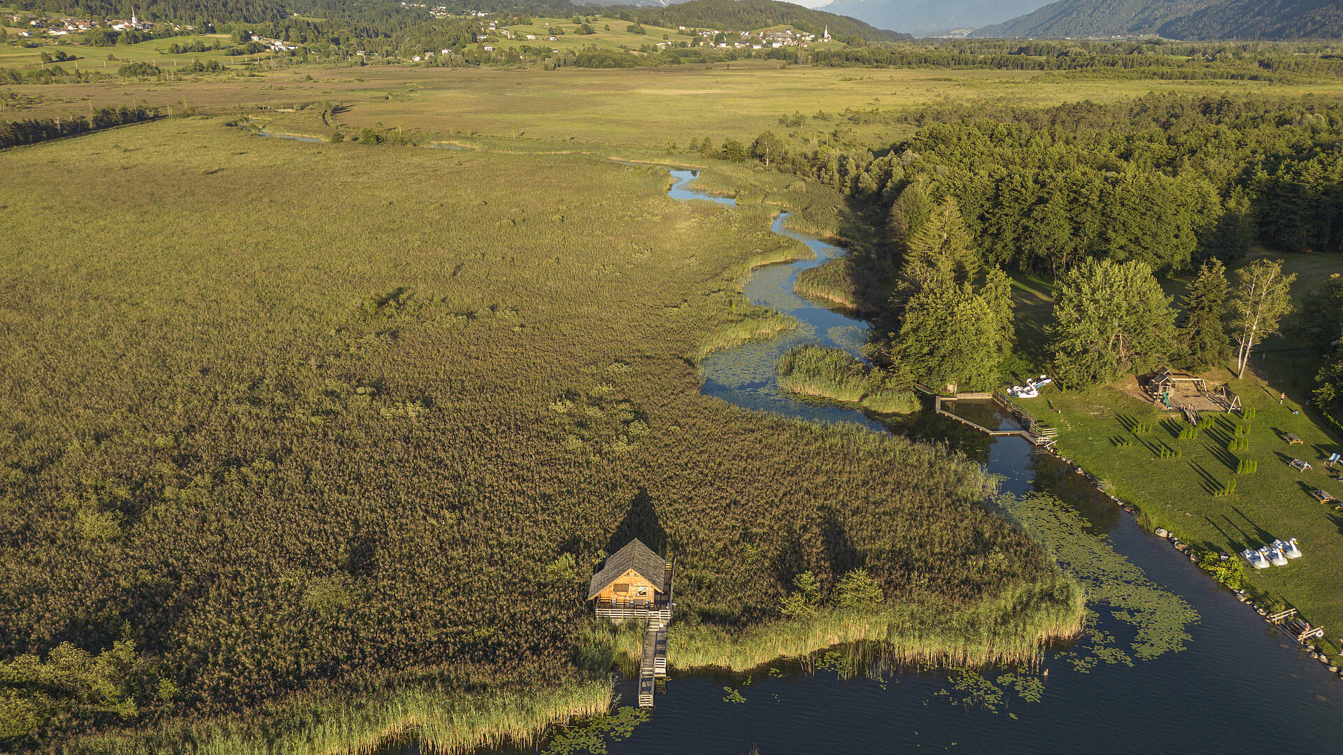 Blick auf den Pressegger See mit Schilfgürtel und Badehäusern