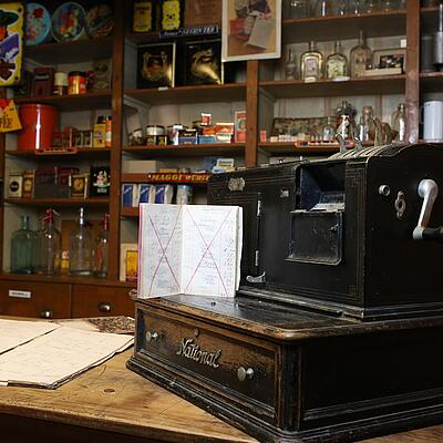 Historische Registrierkasse und Waren in den Regalen im Greißlermuseum Thörl-Maglern.