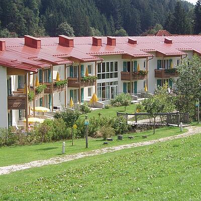 Außenansicht des Thermalbads Weissenbach mit Gebäudekomplex, Balkonen und Gartenbereich