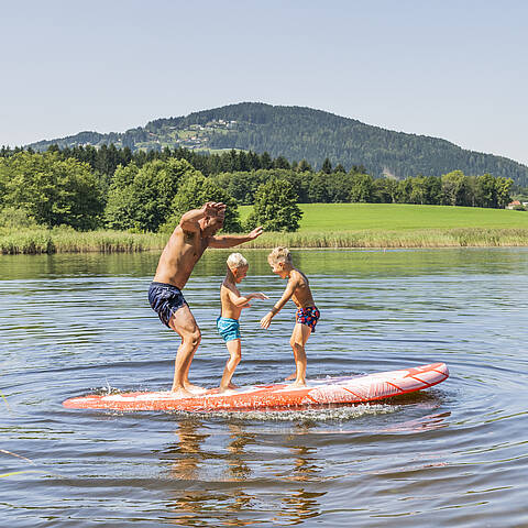 Familie beim Baden und Stand up paddeln im Flatschacher See