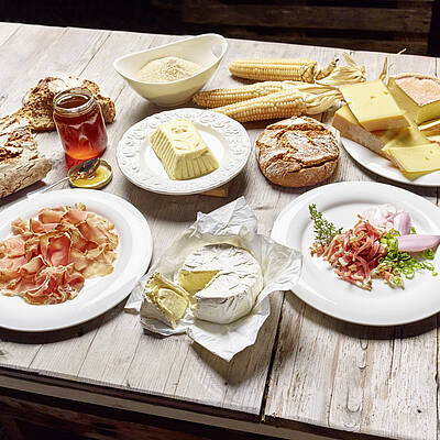 Slow Food in Kärnten am Holztisch mit Schinken Speck Käse Butter Honig