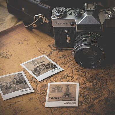 Retro-Kamera auf einer alten Weltkarte mit drei Vintage-Polaroidfotos – Symbolbild für Escape Room Team Mission in Villach.