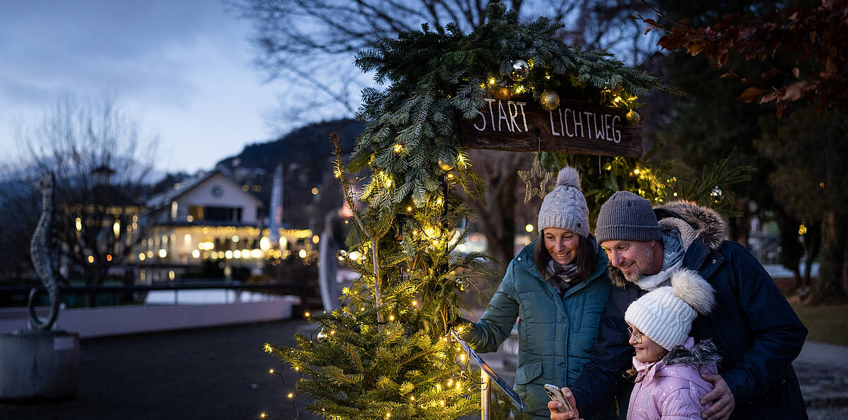 Familie am Millstaetter Lichtweg im Advent neben dem Christbaum
