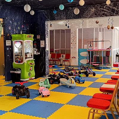 Bunte Indoor-Spielhalle mit Kinderfahrzeugen, Hüpfburgen und Spielbereichen in Klagenfurt