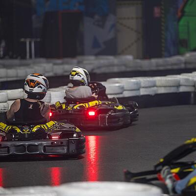 Fahrer in Elektro-Karts auf der Indoor-Kartbahn Kartsport Friesacher in Wolfsberg, bei einer schnellen Kurvenfahrt.