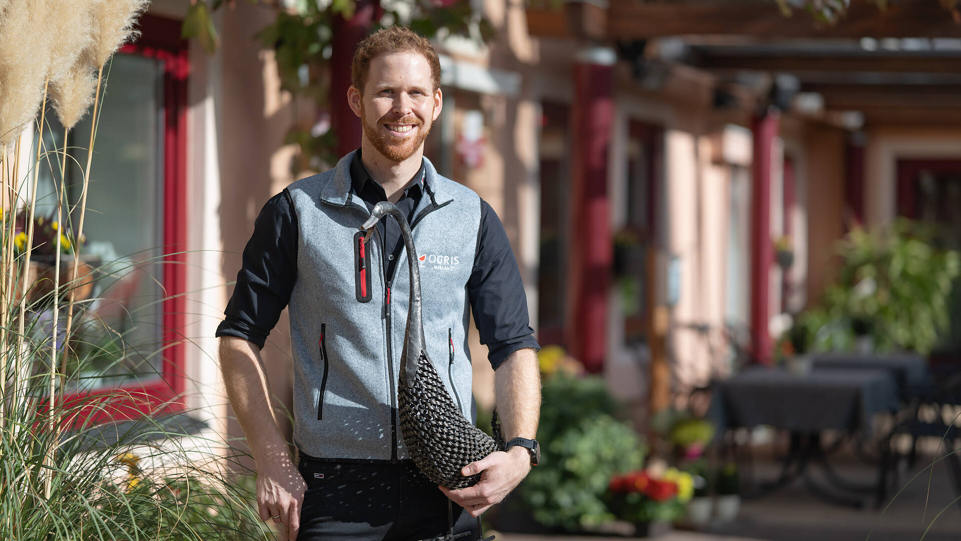 Martin Ogris steht vor dem herbstlich dekorierten Gasthaus Ogris in Ludmannsdorf und hält eine Gans-Skulptur in der Hand.