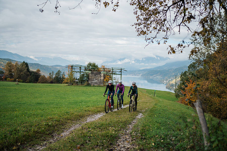 Drei Gravelbiker radeln mit herrlichem Blick über den Millstätter See – Kärnten von seiner schönsten Seite.