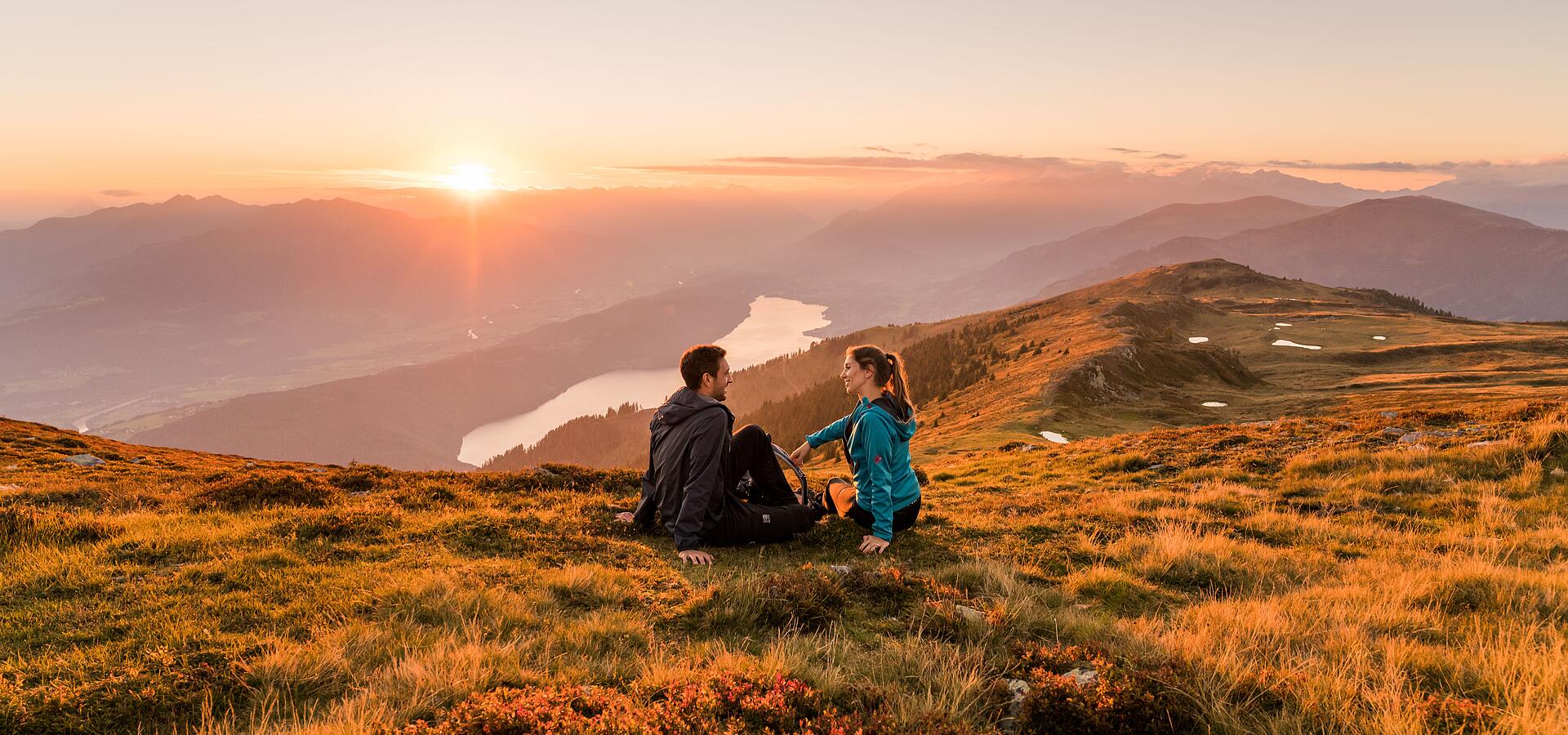 Frau und Mann genießen den Sonnenaufgang im Herbst am Mirnock