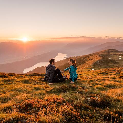 Frau und Mann genießen den Sonnenaufgang im Herbst am Mirnock