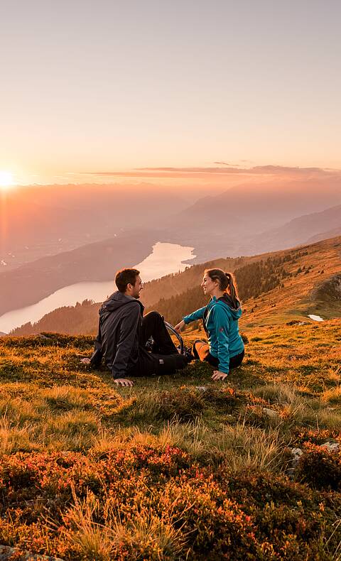 Frau und Mann genießen den Sonnenaufgang im Herbst am Mirnock