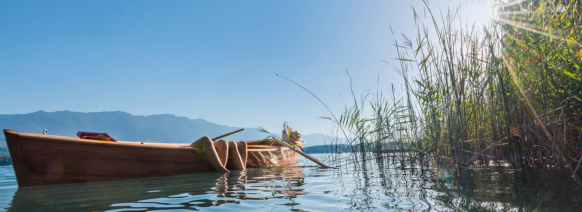 Ruderboot am Faaker See mit Füßen im Wasser