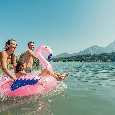 Familie spielt im Wassser am blauen Faaker See und hat Spass