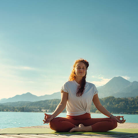 Frau macht Yogaübungen am Faaker See 