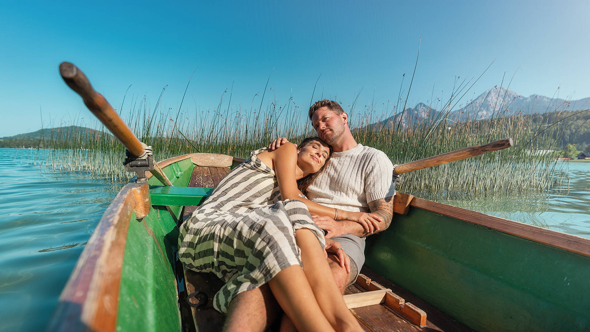 Frau und Mann liegen im Ruderboot und genießen die Sonne