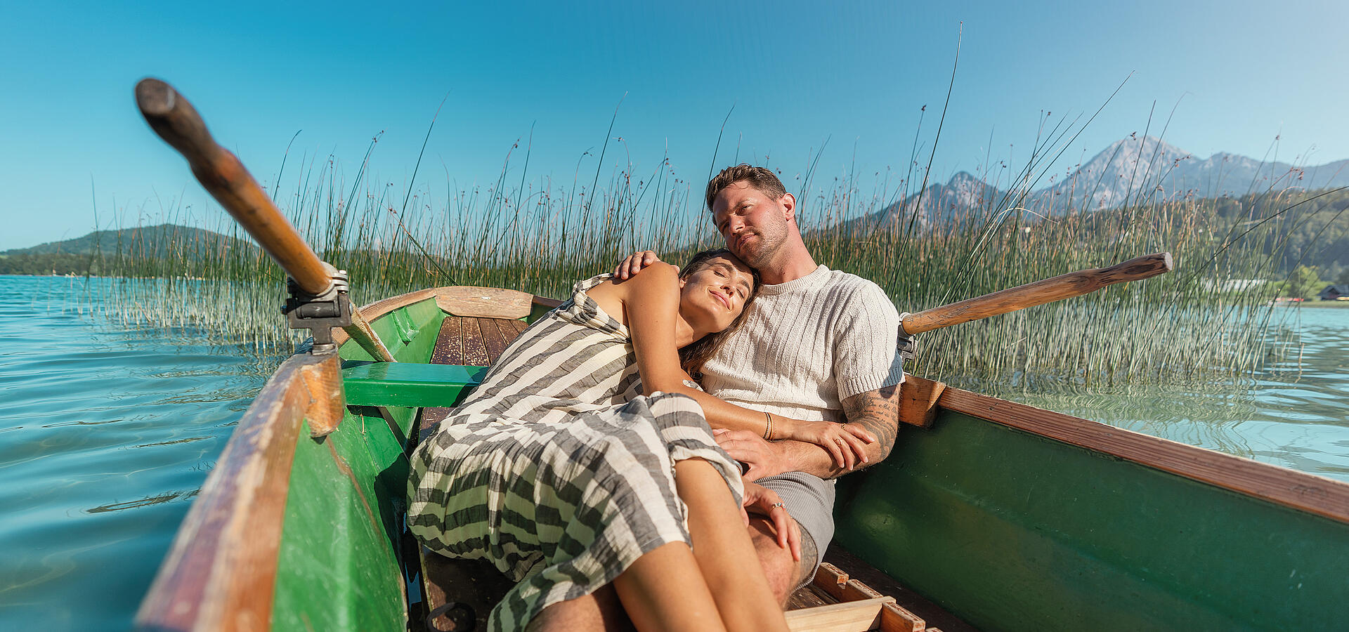 Frau und Mann liegen im Ruderboot und genießen die Sonne