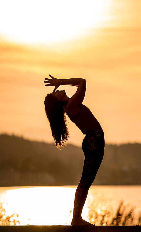 Frau macht Yogaübung beim Sonnenuntergang am Wörthersee im Herbst